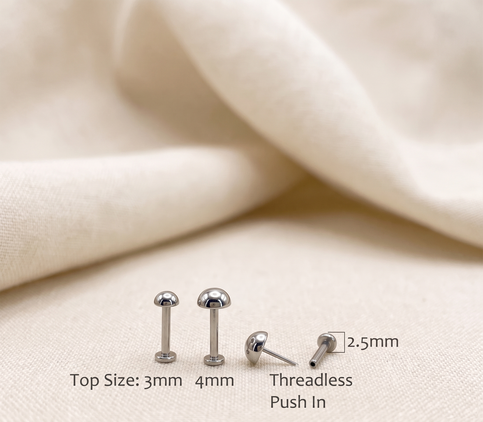 Silver earrings with size labels on a beige fabric background