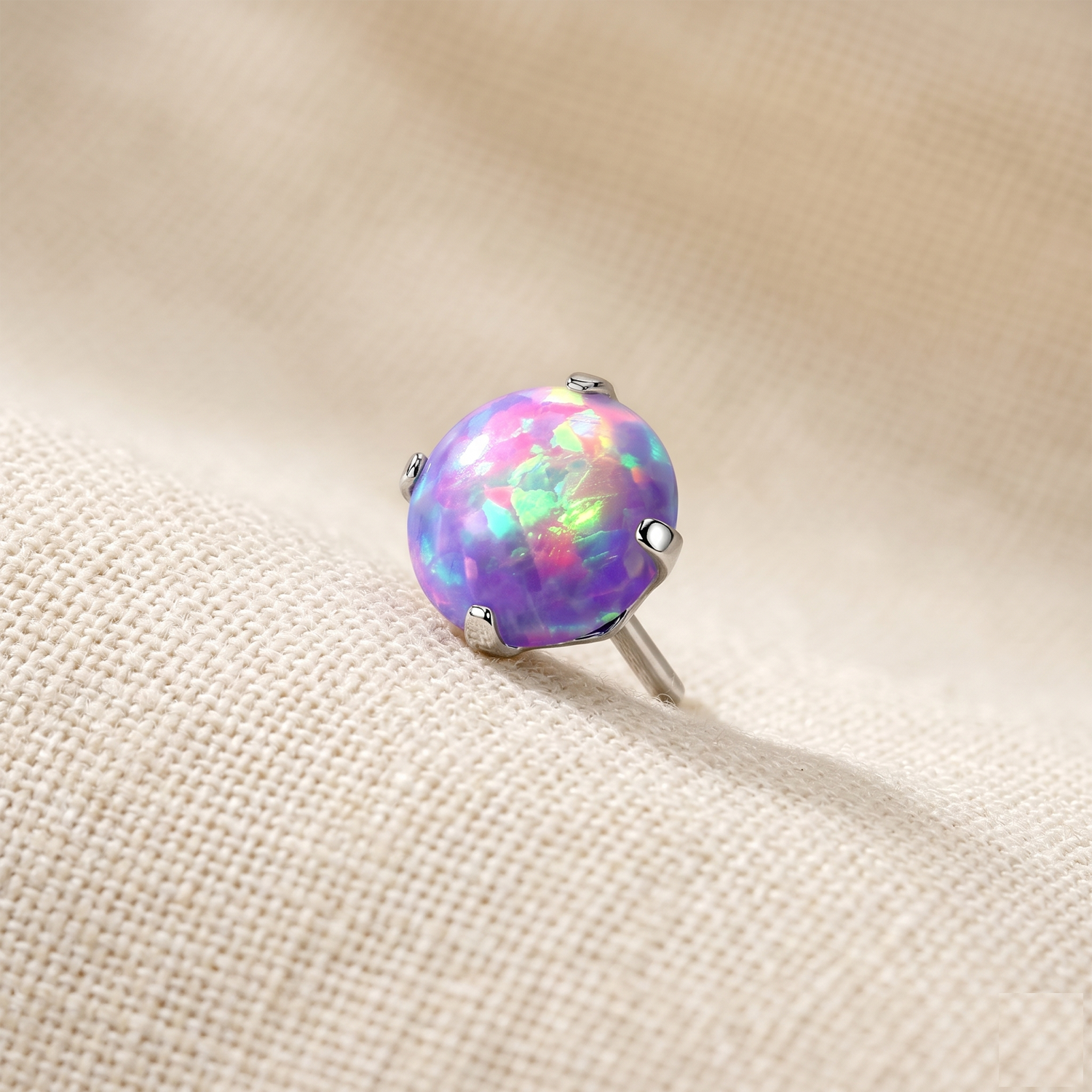 Opal stud earring on a beige fabric background