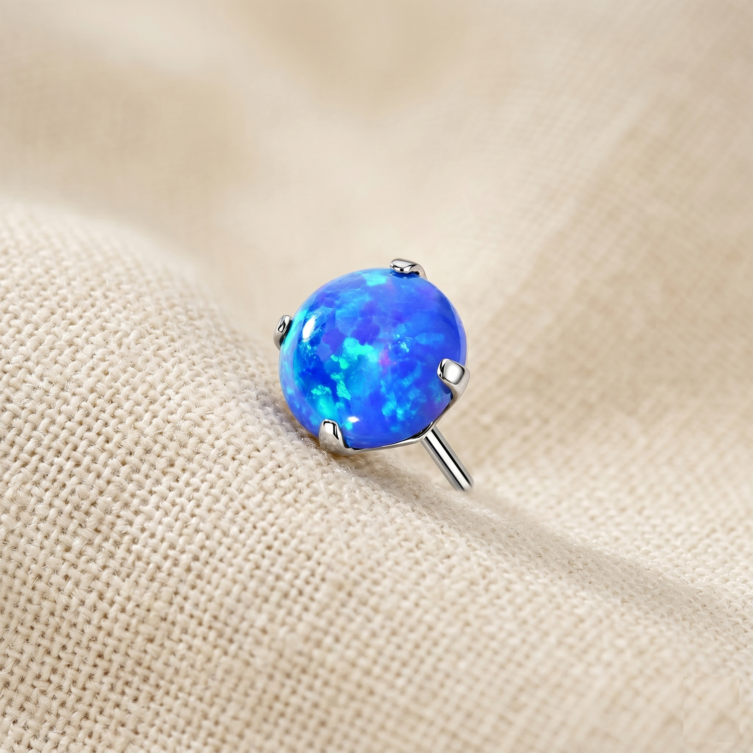 Blue opal stud earring on a beige fabric background