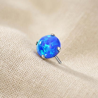 Blue opal stud earring on a beige fabric background