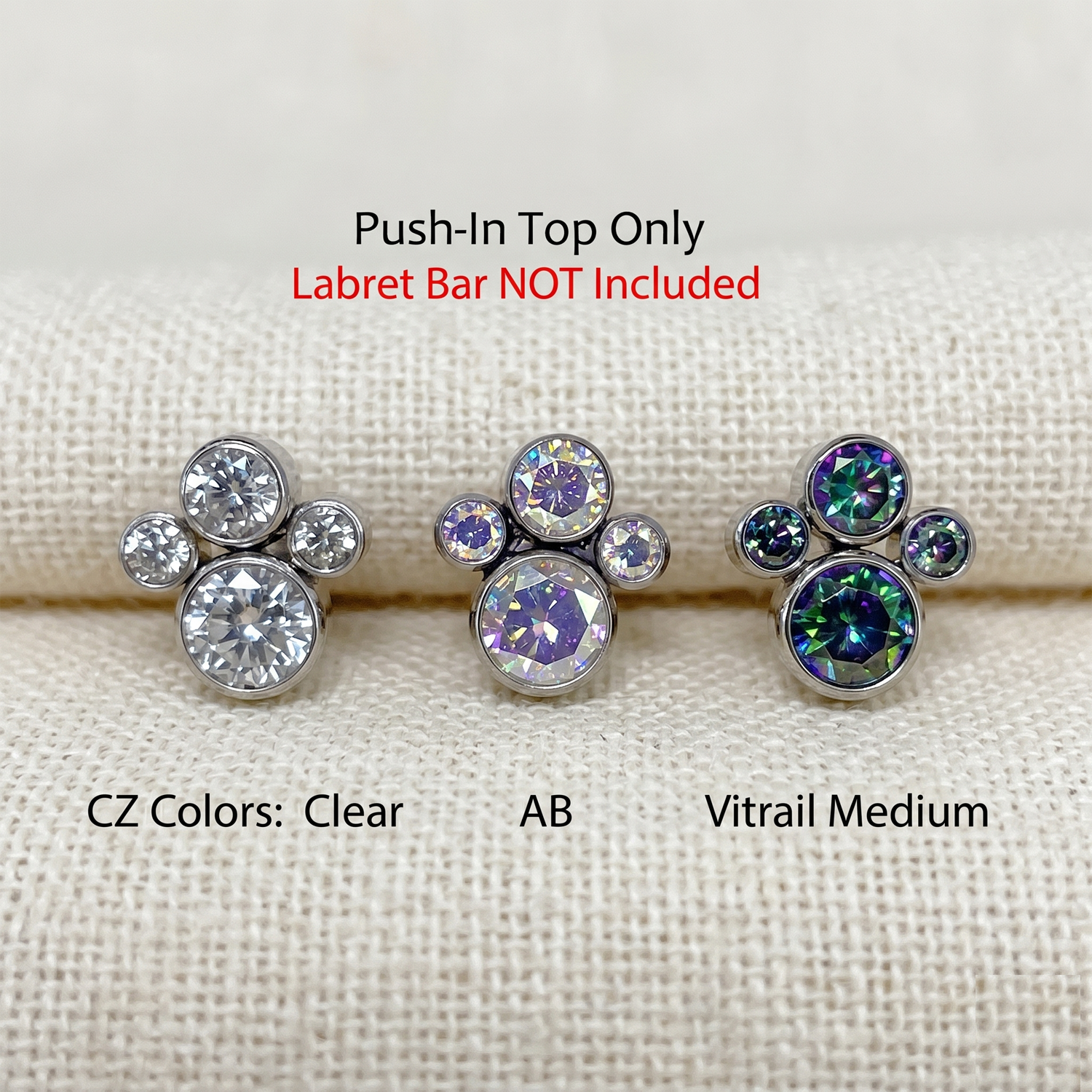Three labret top jewelry pieces with different color options on a textured beige background.