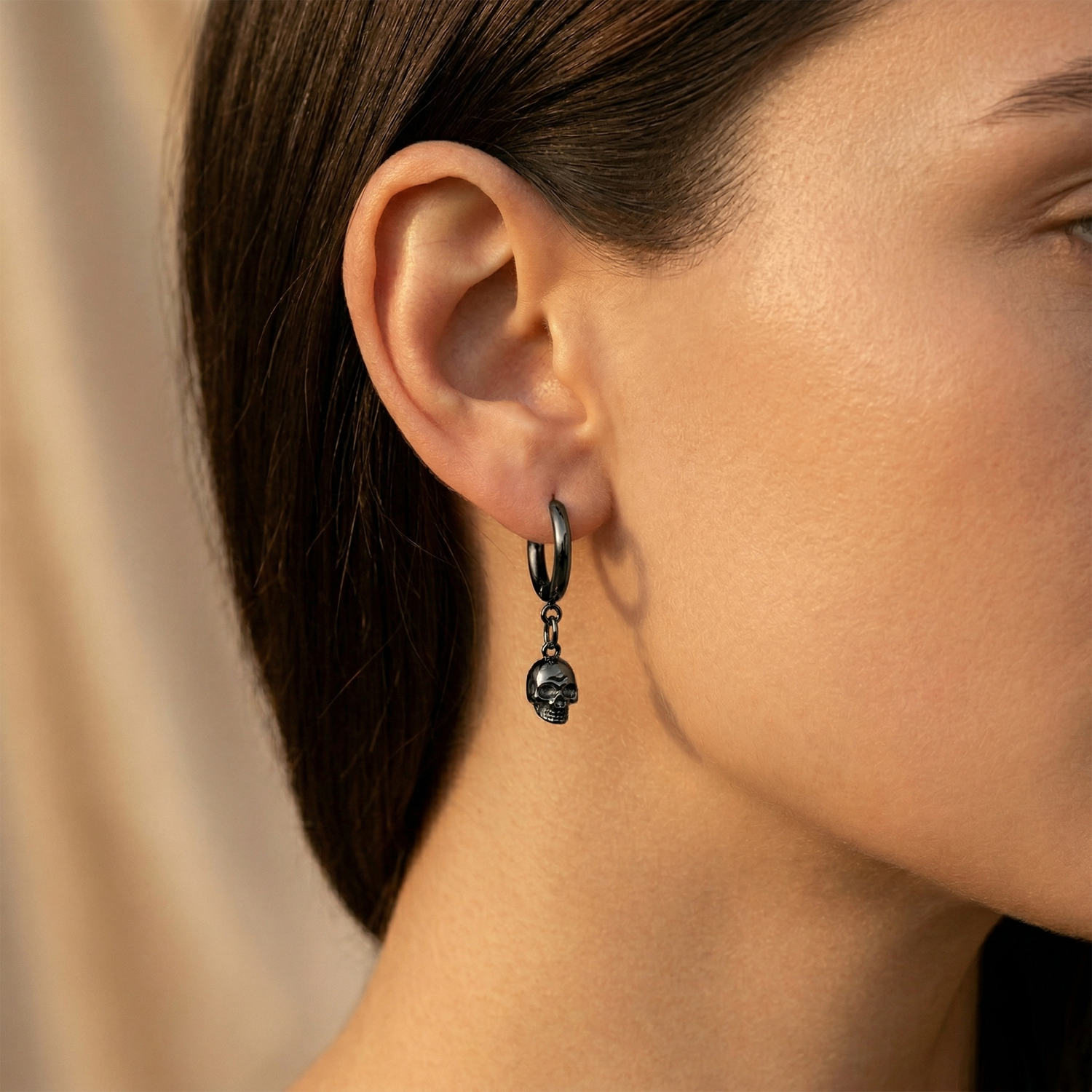 black surgical steel skull dangle hoop earring shown on ear