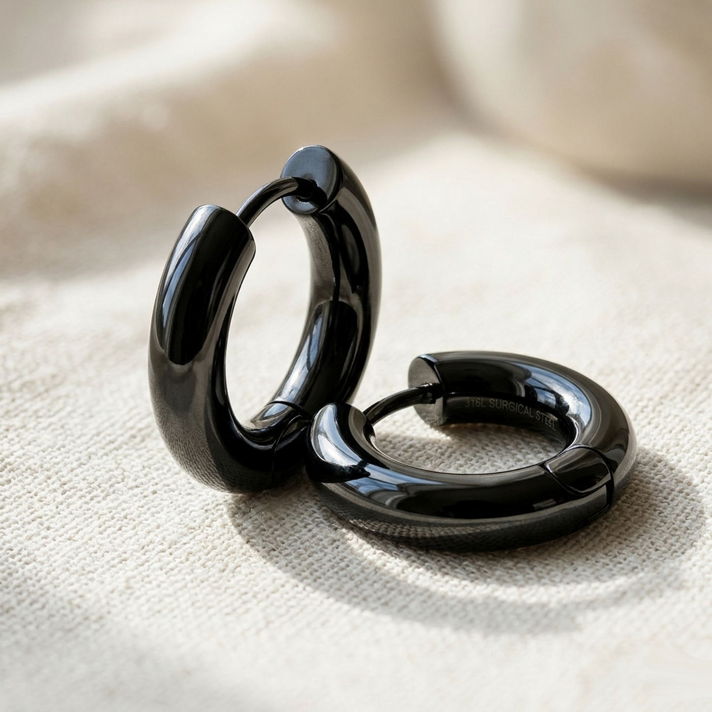 Black surgical steel thick 5mm hoop earrings on cream linen fabric