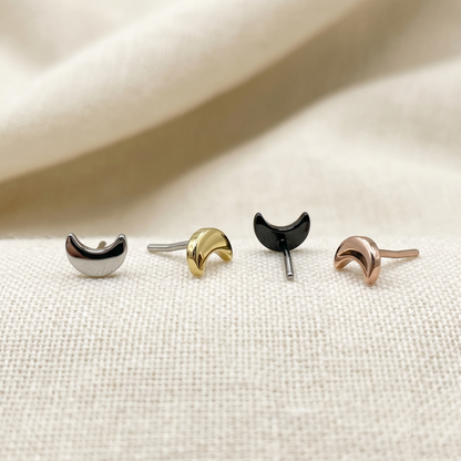 Set of four crescent moon-shaped earrings on a beige fabric background