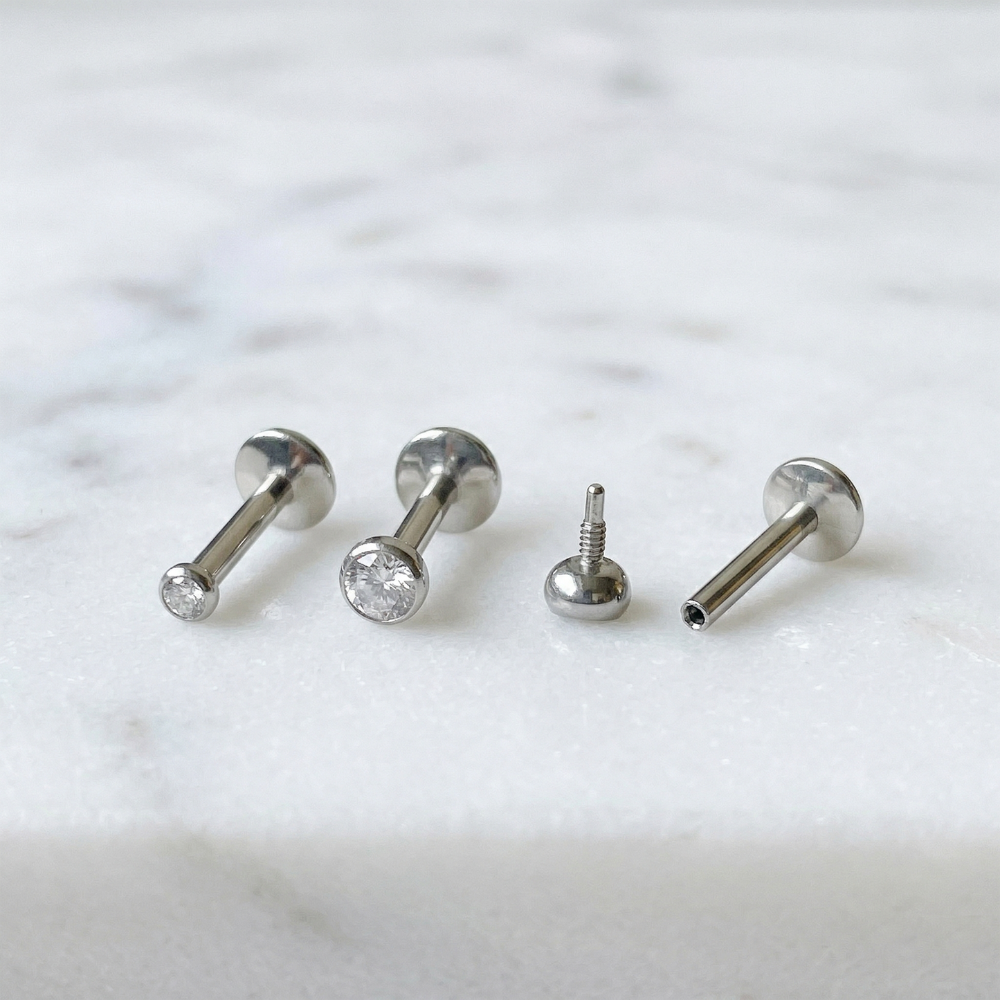 Titanium bezel CZ convex threaded labret studs 2mm and 3mm sizes on marble