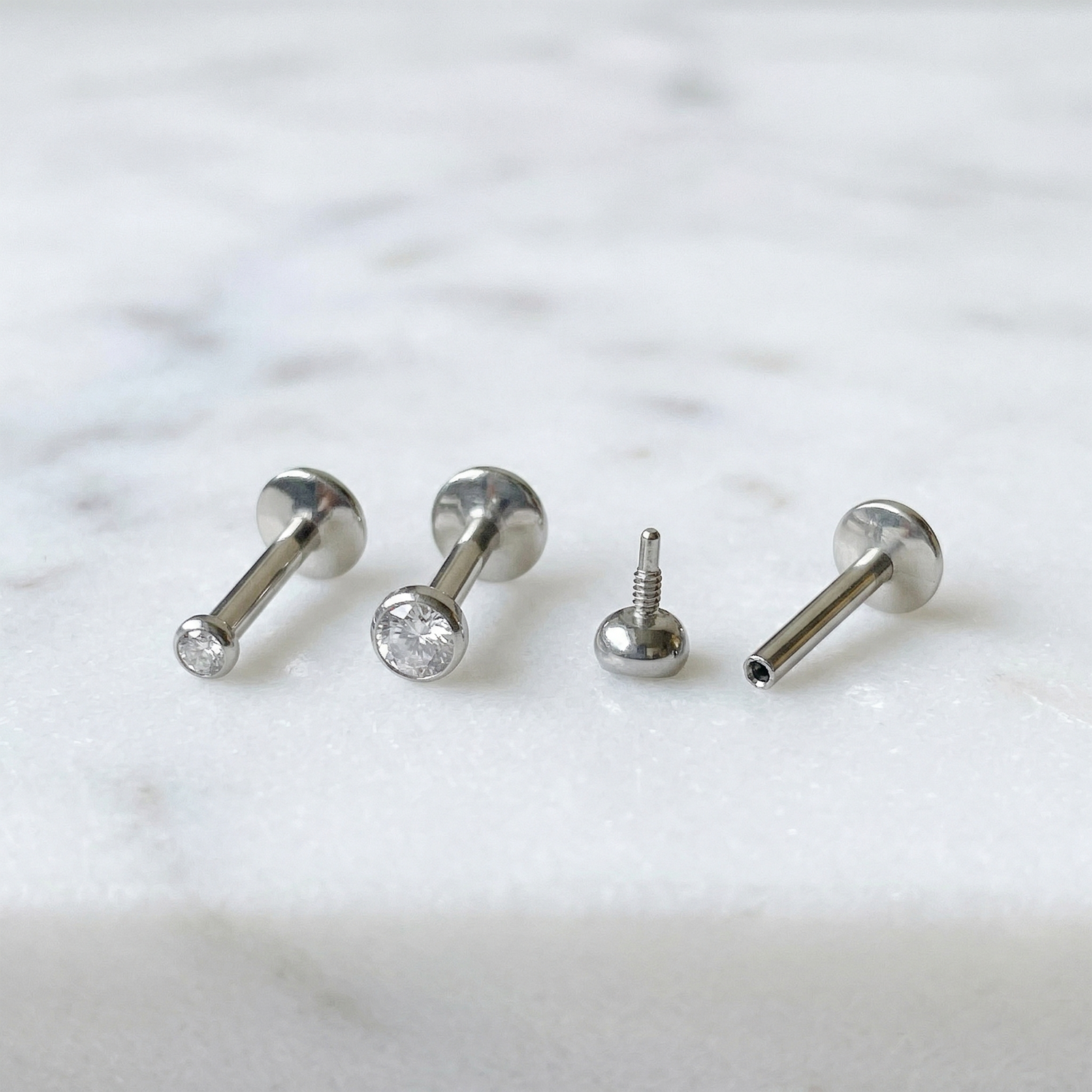 Titanium bezel CZ convex threaded labret studs 2mm and 3mm sizes on marble