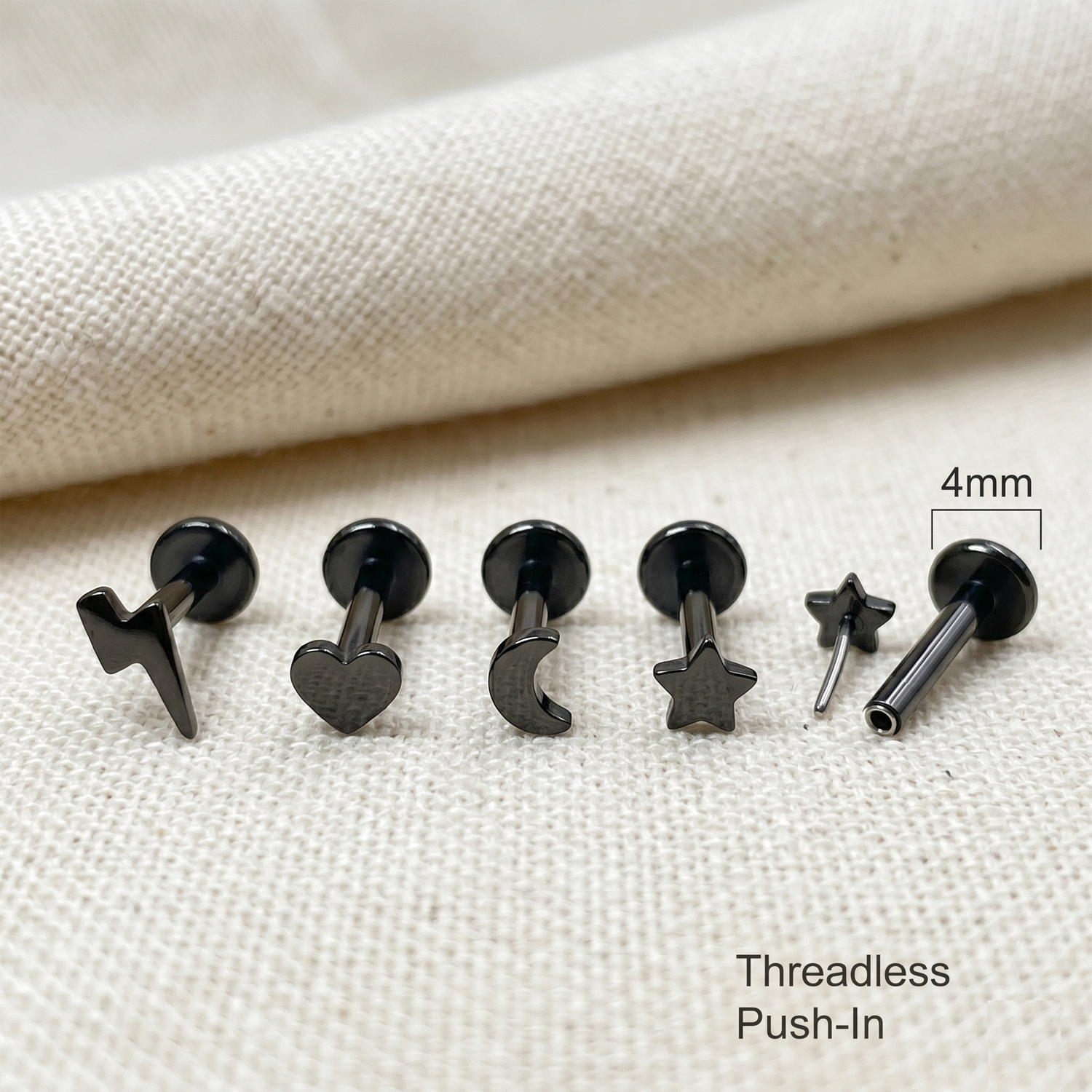 Set of black threadless push-in earrings on a beige fabric background