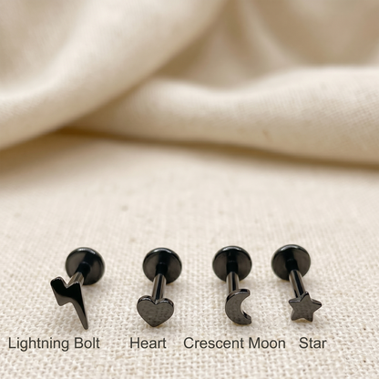Set of black metal earrings with different shapes on a beige fabric background