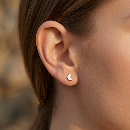 Silver titanium crescent moon stud earring shown on ear with earlobe piercing