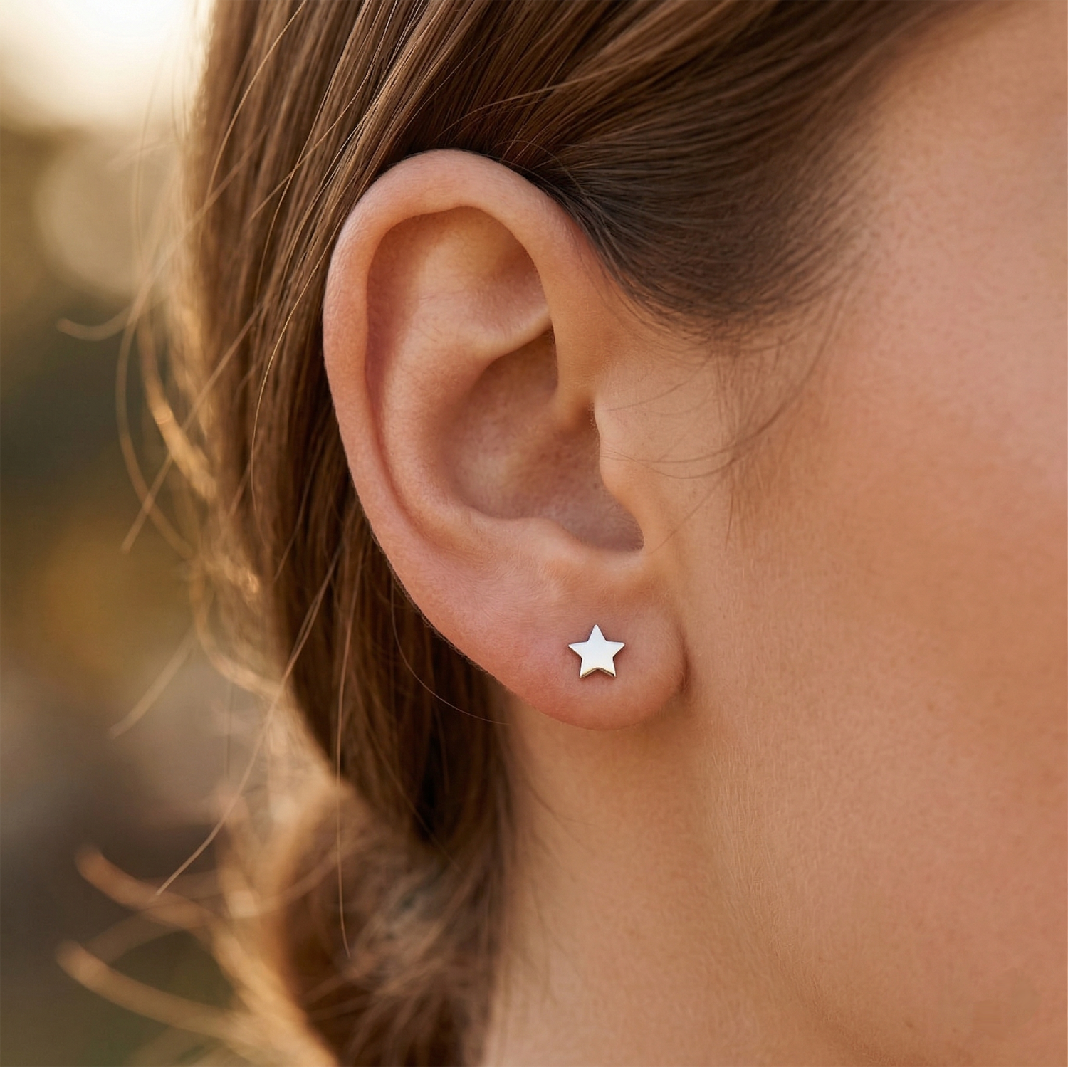 Silver titanium star stud earring shown on ear with earlobe piercing