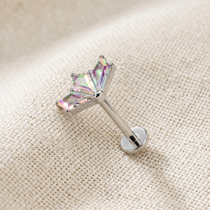 Silver stud earring with a colorful gemstone on a beige fabric background