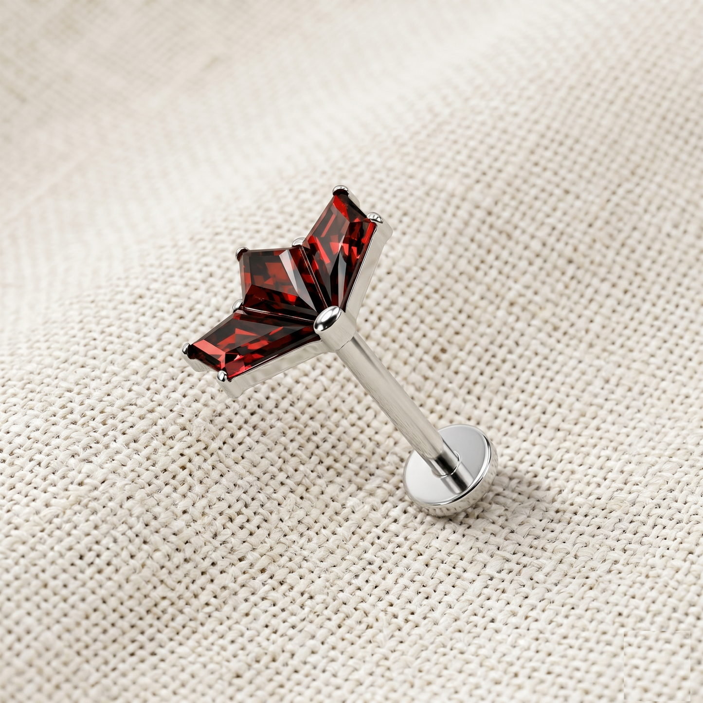 Silver barbell with red gemstones on a beige textured background