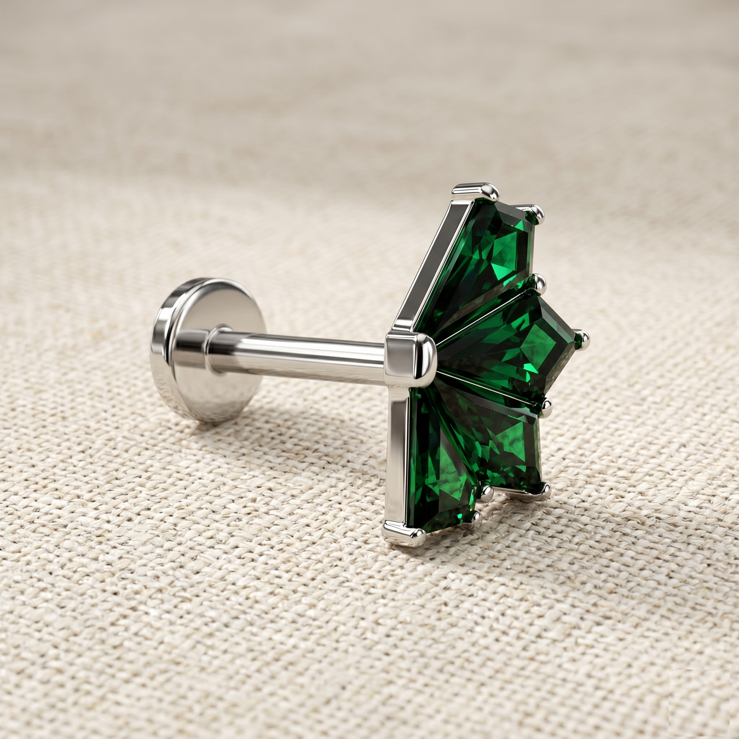 Silver barbell with green gemstones on a beige fabric background