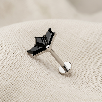 Silver lip ring with black gemstone on a beige fabric background