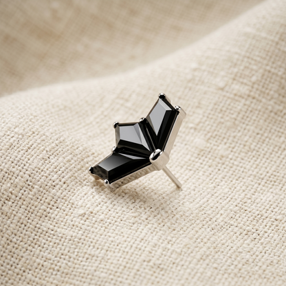 Black gemstone earring on a beige fabric background