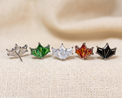 Five star-shaped earrings in different colors on a beige fabric background
