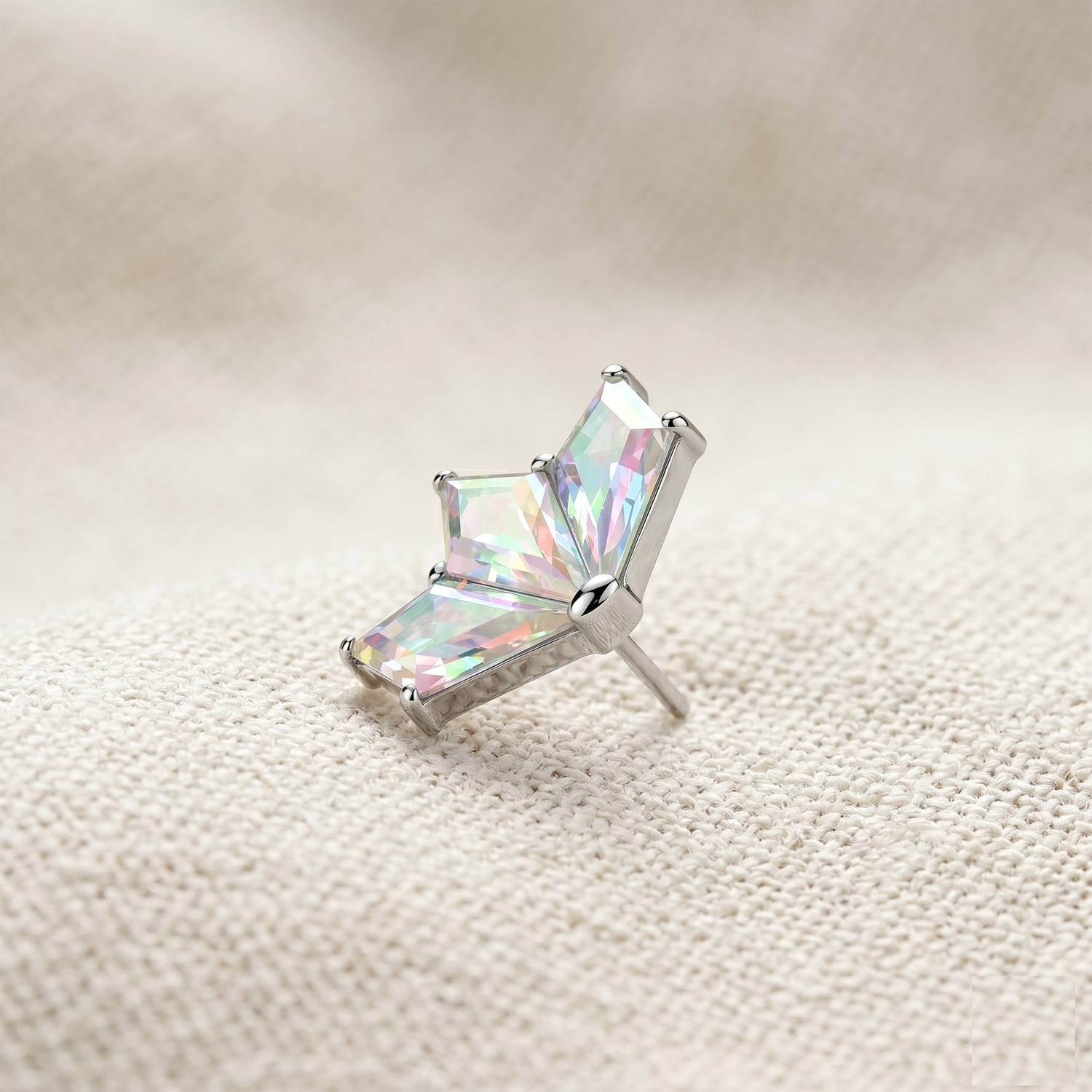 Silver earring with a multicolored gemstone on a textured beige surface