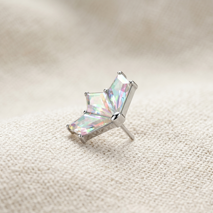 Silver earring with a multicolored gemstone on a textured beige surface