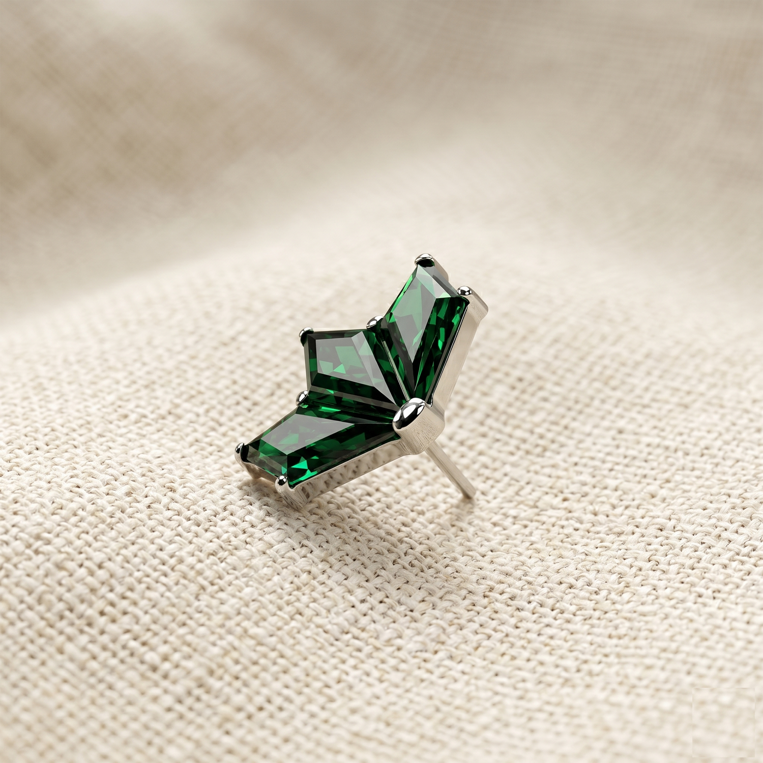 Green gemstone brooch on a beige fabric background