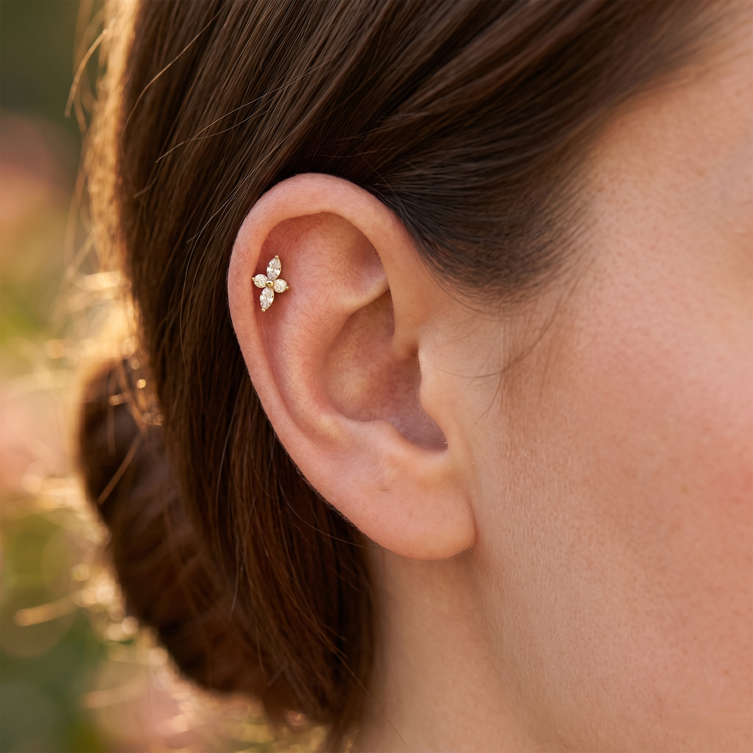 Close-up of an ear with a delicate earring against a blurred natural background