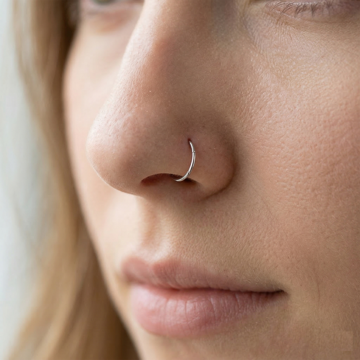 Silver titanium hinged hoop shown on nostril piercing