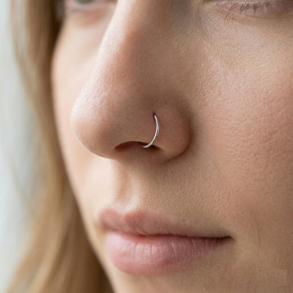 Silver nose hoop shown on nostril piercing