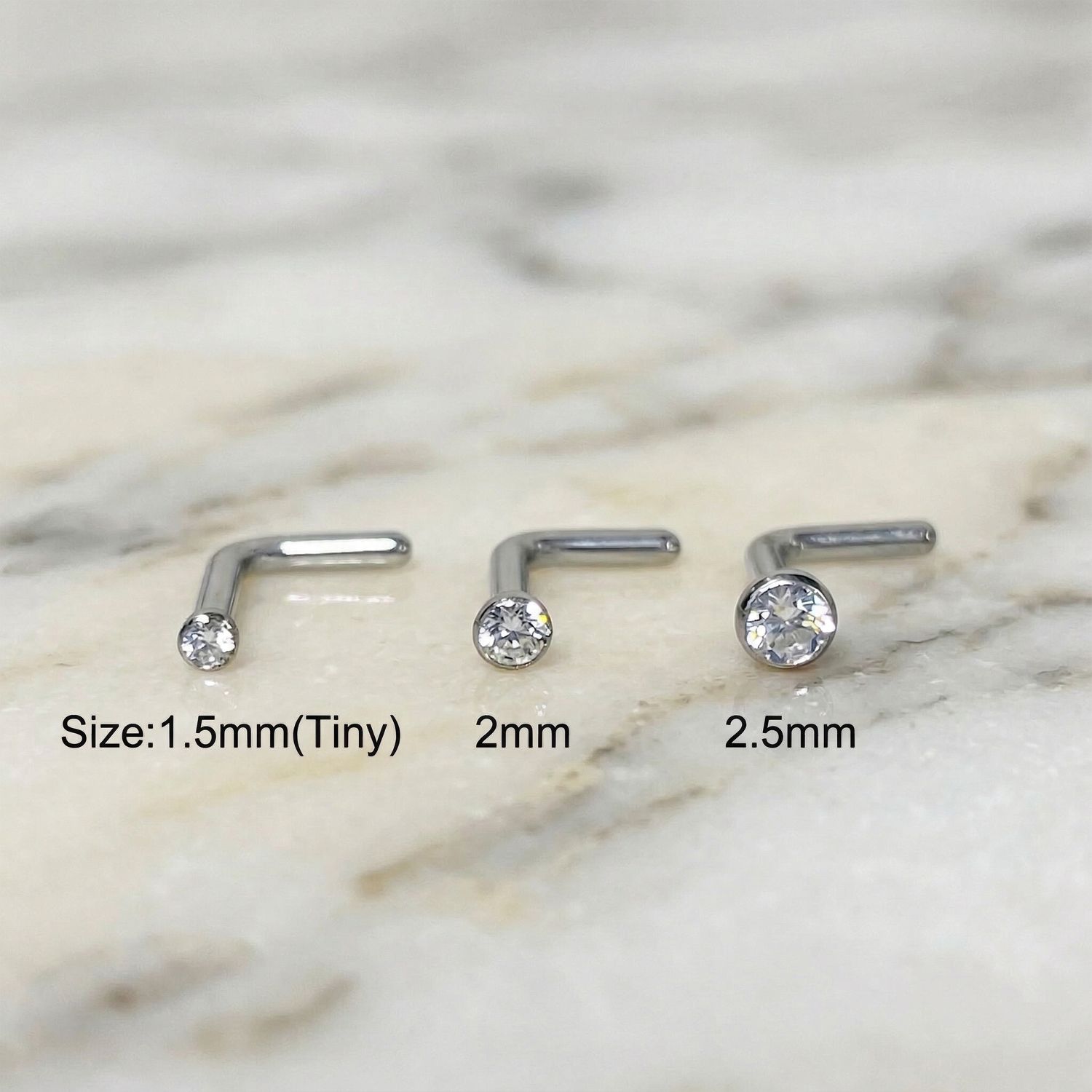 Titanium CZ L-bend nose studs size comparison 1.5mm 2mm 2.5mm on marble