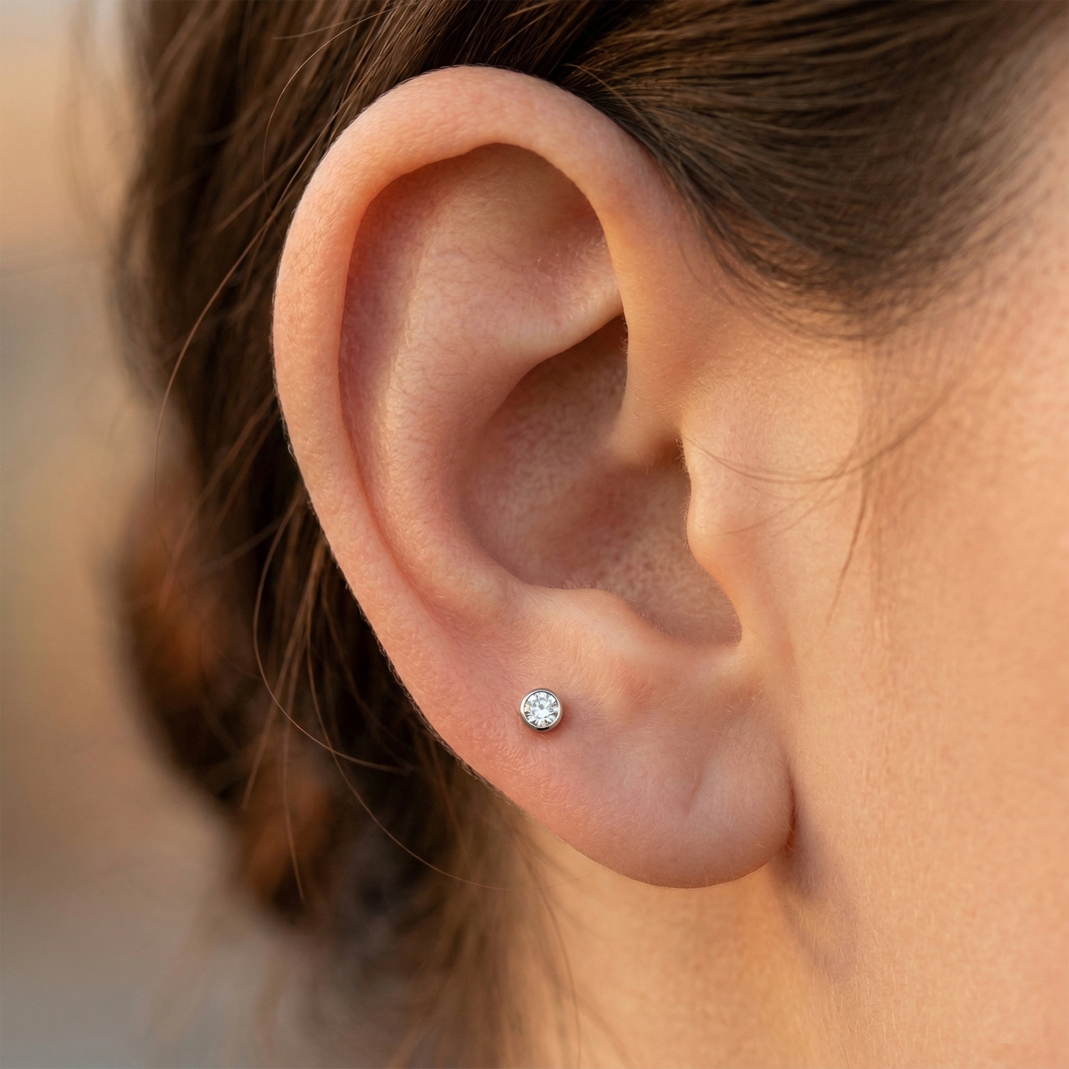 Clear CZ bezel studs shown as lobe piercing