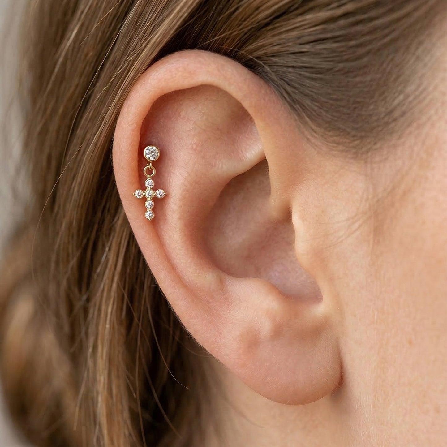 Titanium CZ cross dangle stud shown on ear with helix piercing
