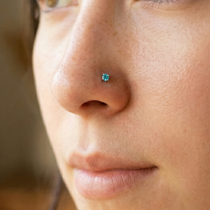 Titanium aqua CZ prong stud shown on nostril piercing
