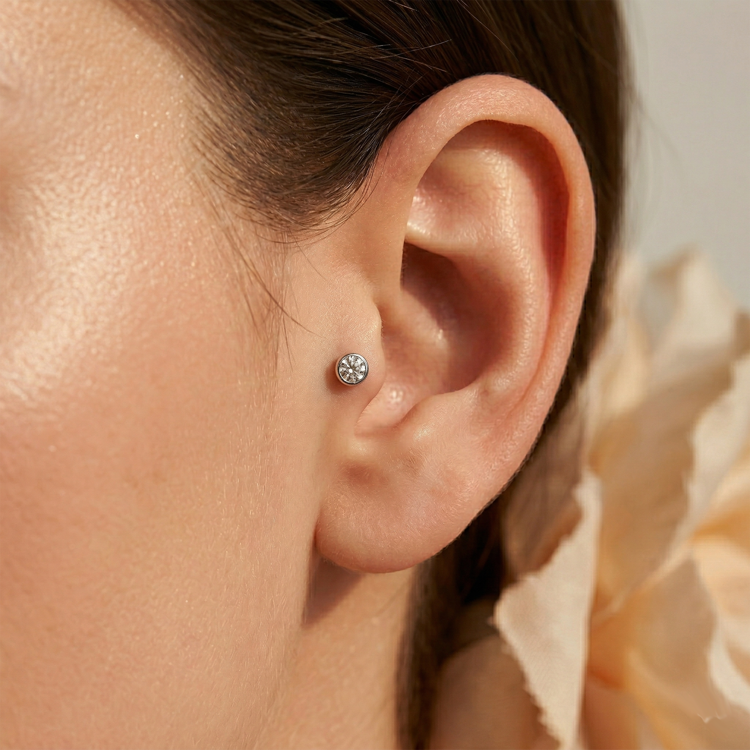 Silver titanium bezel CZ convex threaded labret shown on tragus piercing