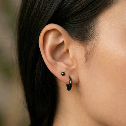 Black surgical steel ball stud earrings close-up on ear with lobe piercing