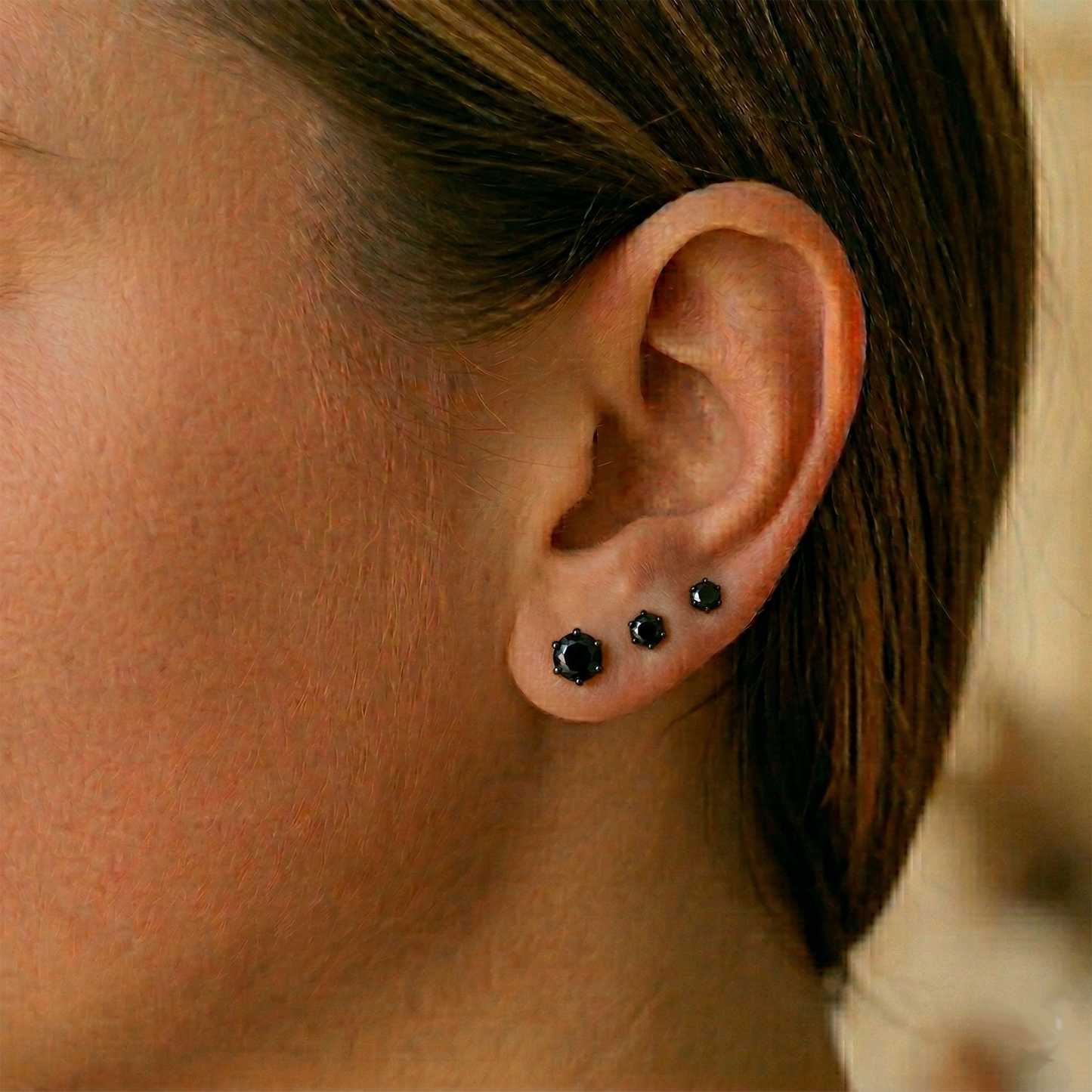 Black CZ surgical steel stud earrings shown on ear with lobe piercing