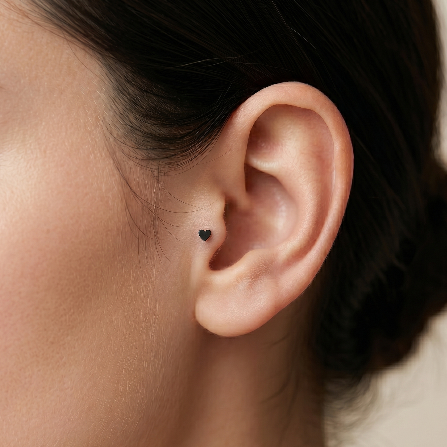 Close-up of an ear with a small black heart-shaped earring.