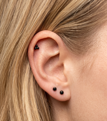 Close-up of an ear with black earrings and blonde hair.