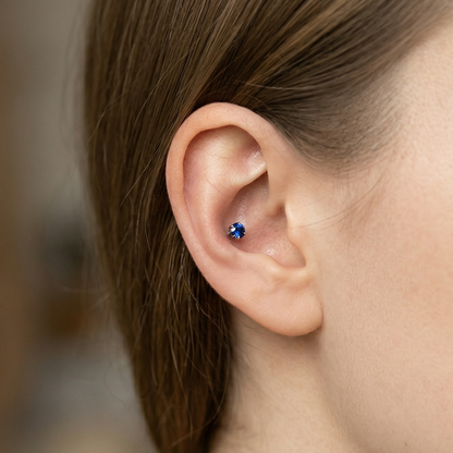 Titanium blue CZ prong stud shown on conch piercing
