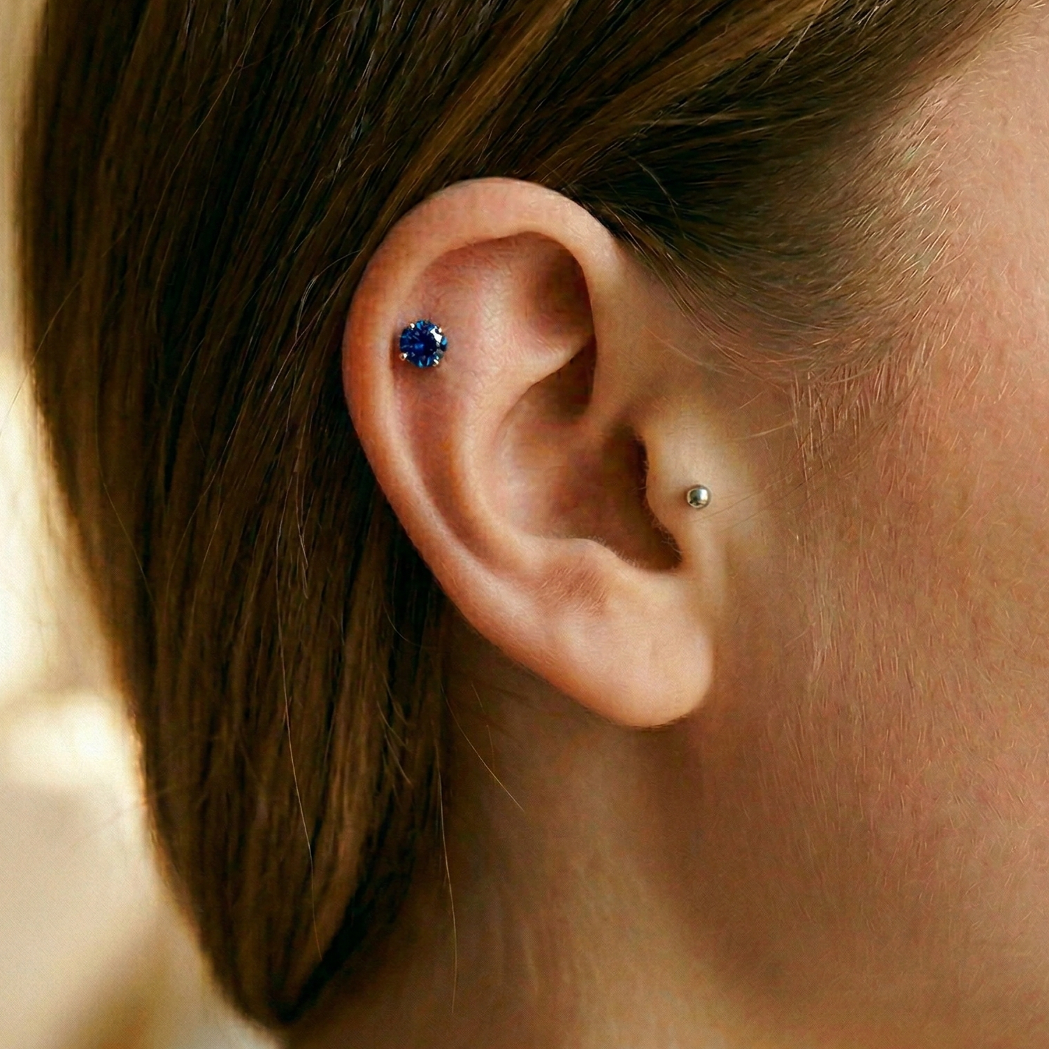 Titanium blue CZ prong stud shown on helix piercing
