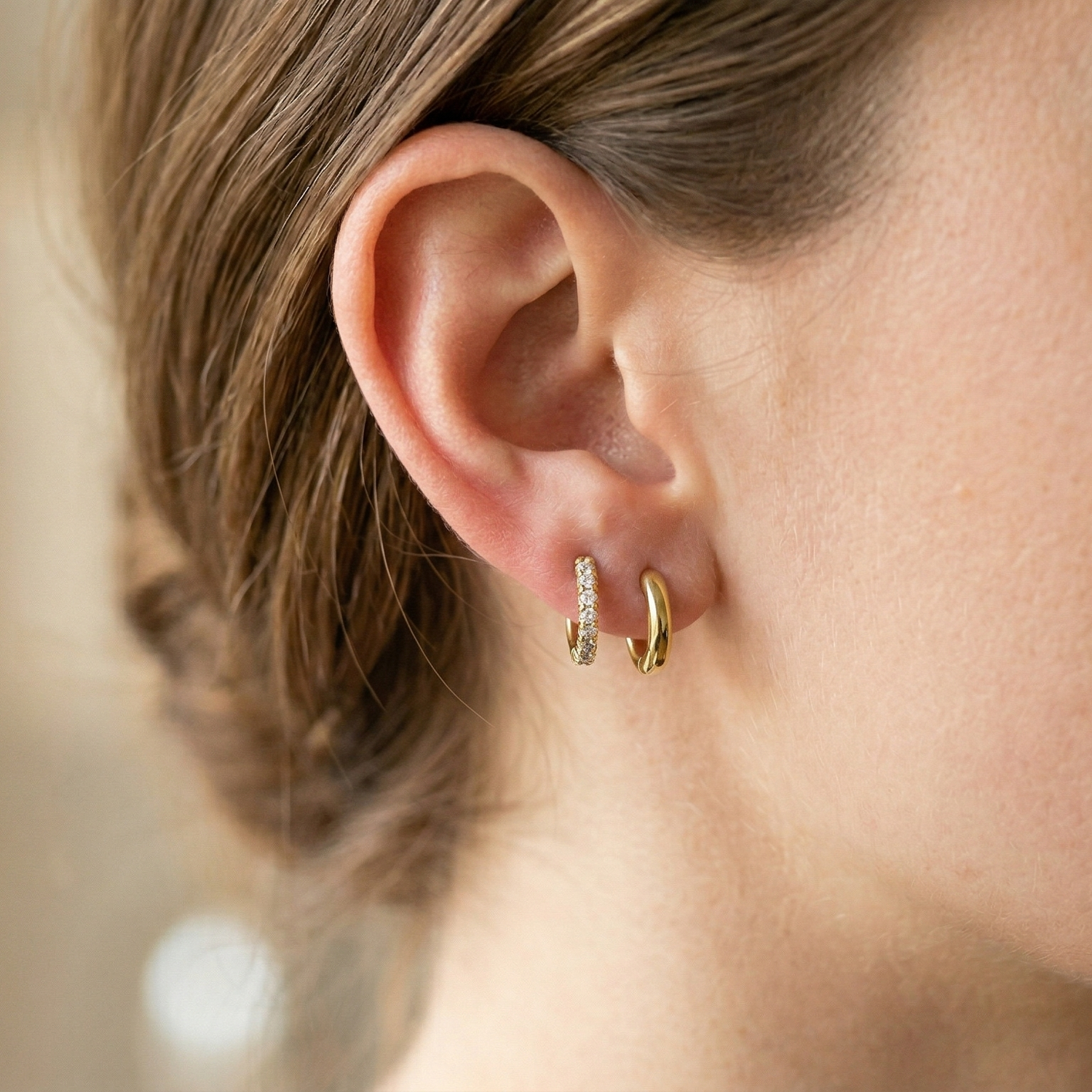 Gold titanium CZ huggie hoop earrings shown on double lobe with plain huggie
