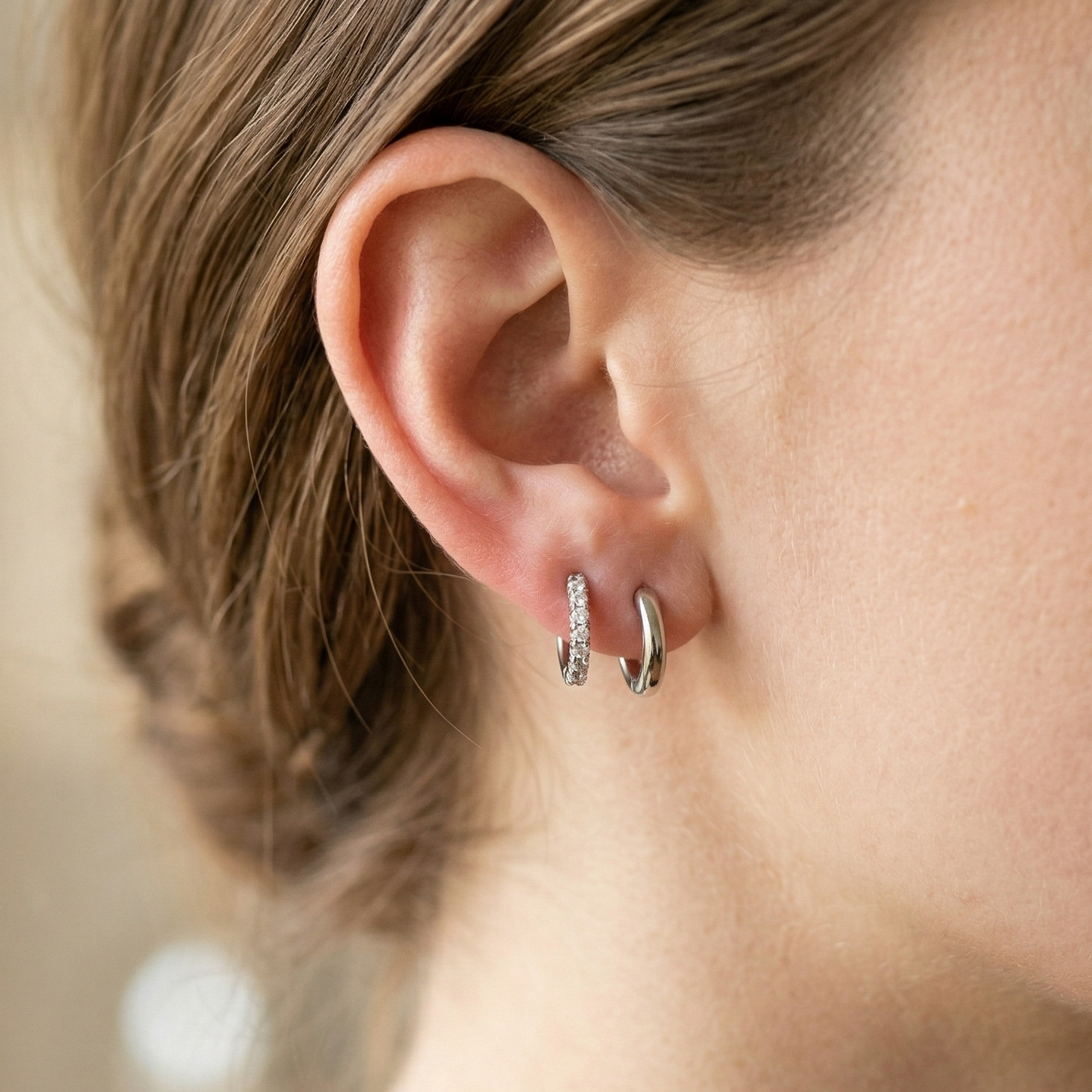 Silver titanium CZ huggie hoop earrings shown on double lobe with plain huggie

