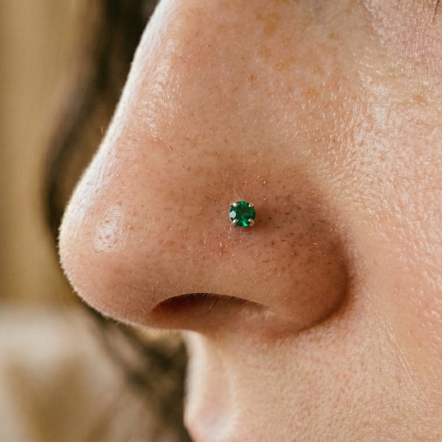 Titanium emerald green CZ prong stud shown on nostril piercing
