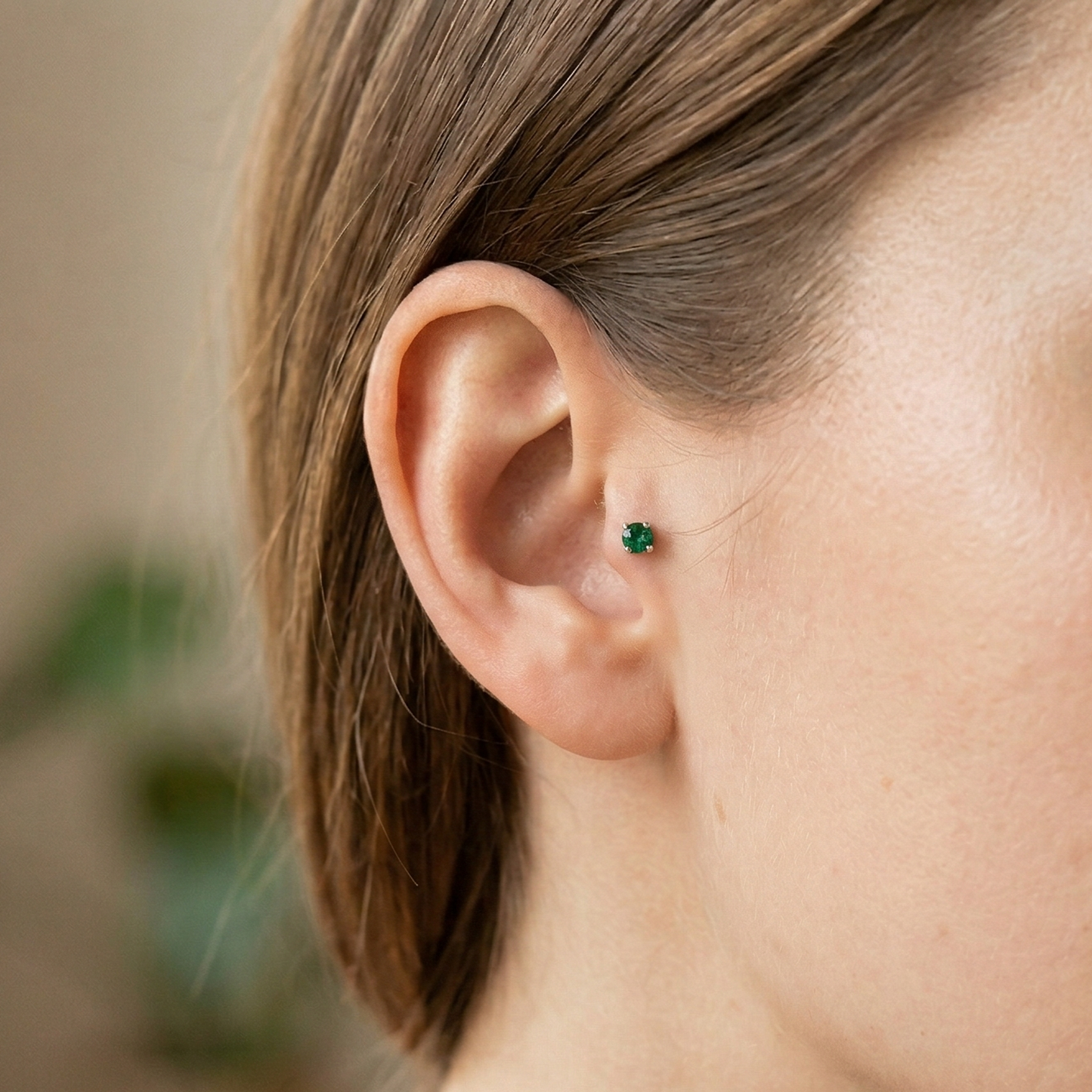 Titanium emerald green CZ prong stud shown on tragus piercing
