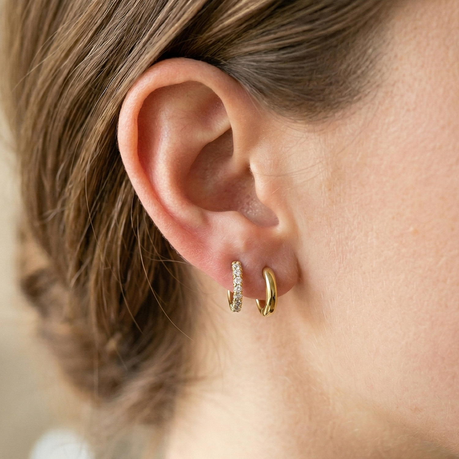 Surgical steel CZ huggie hoop earrings on ear with lobe piercing side view