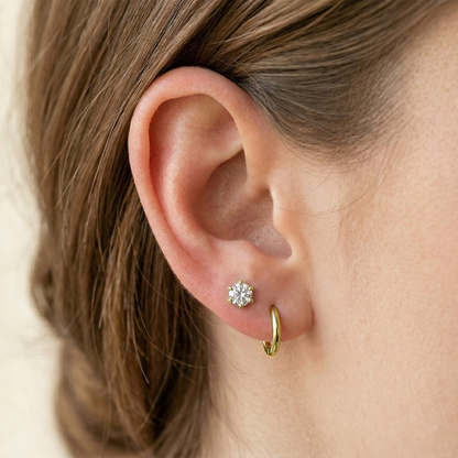 Gold surgical steel clear CZ stud earrings shown on ear with lobe piercing