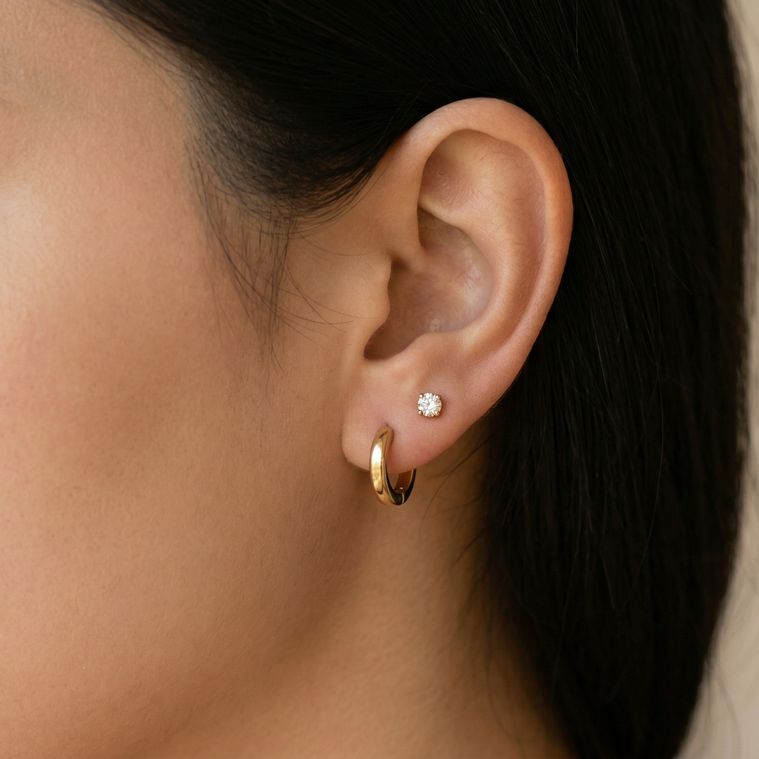 Gold titanium clear CZ stud earring shown on ear with lobe piercing