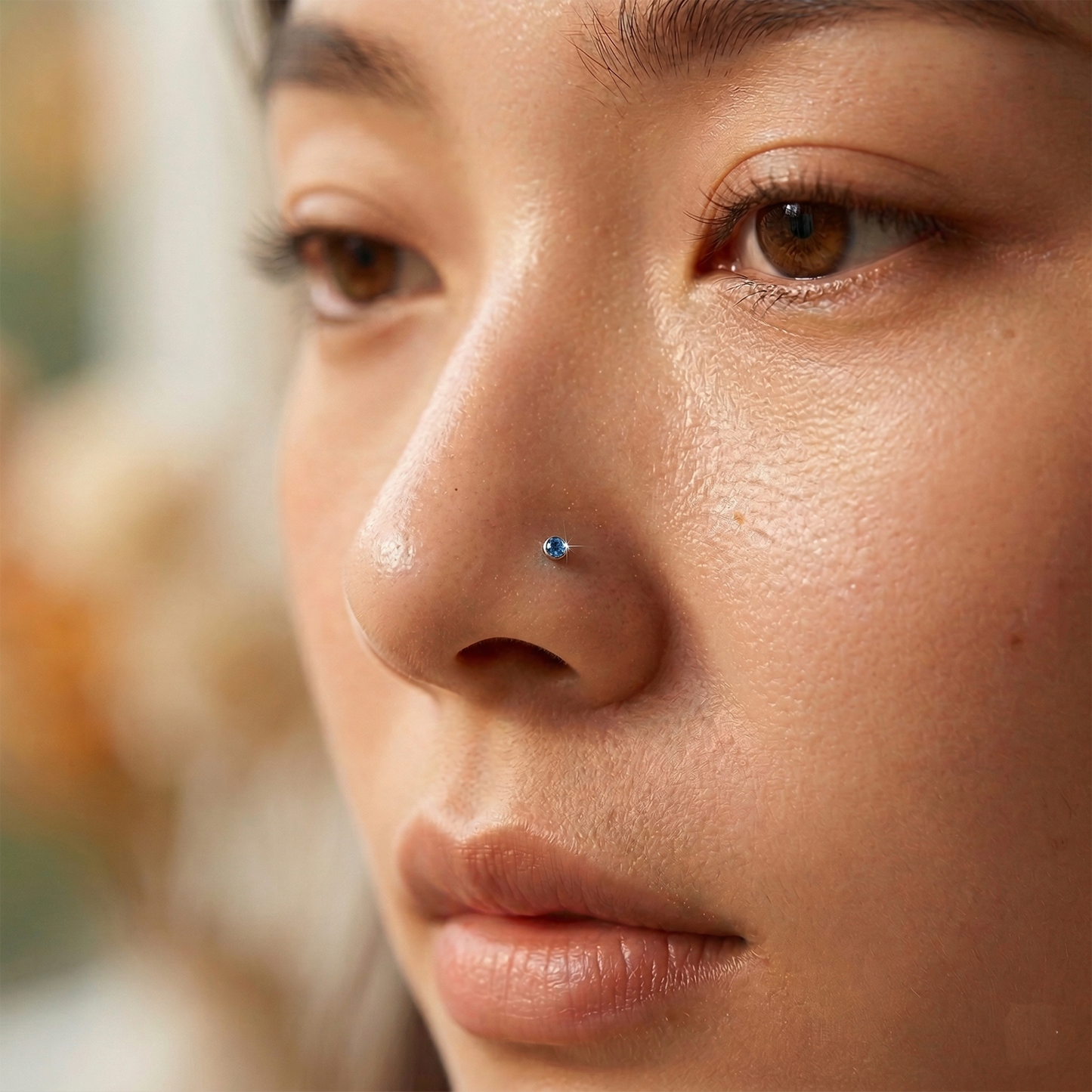 Aqua blue CZ bezel stud shown on nose ring piercing