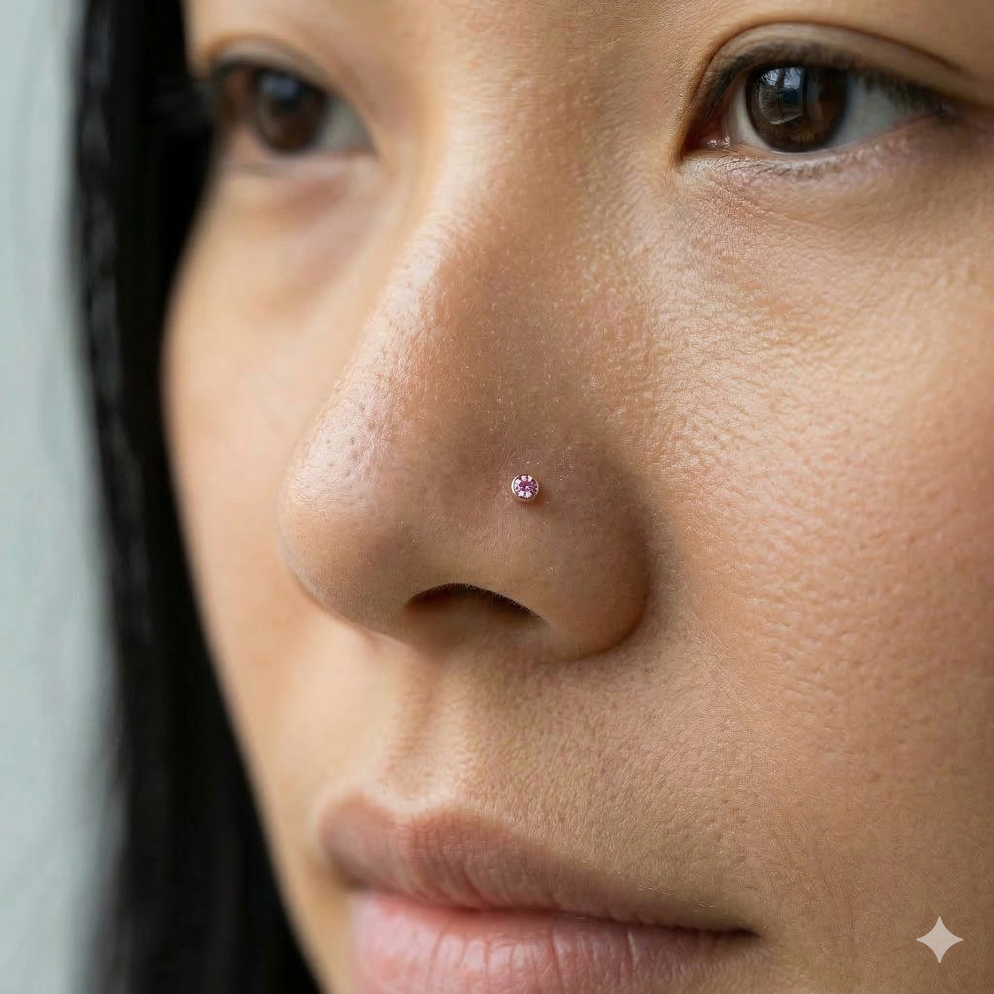 Pink CZ bezel stud shown on nostril piercing