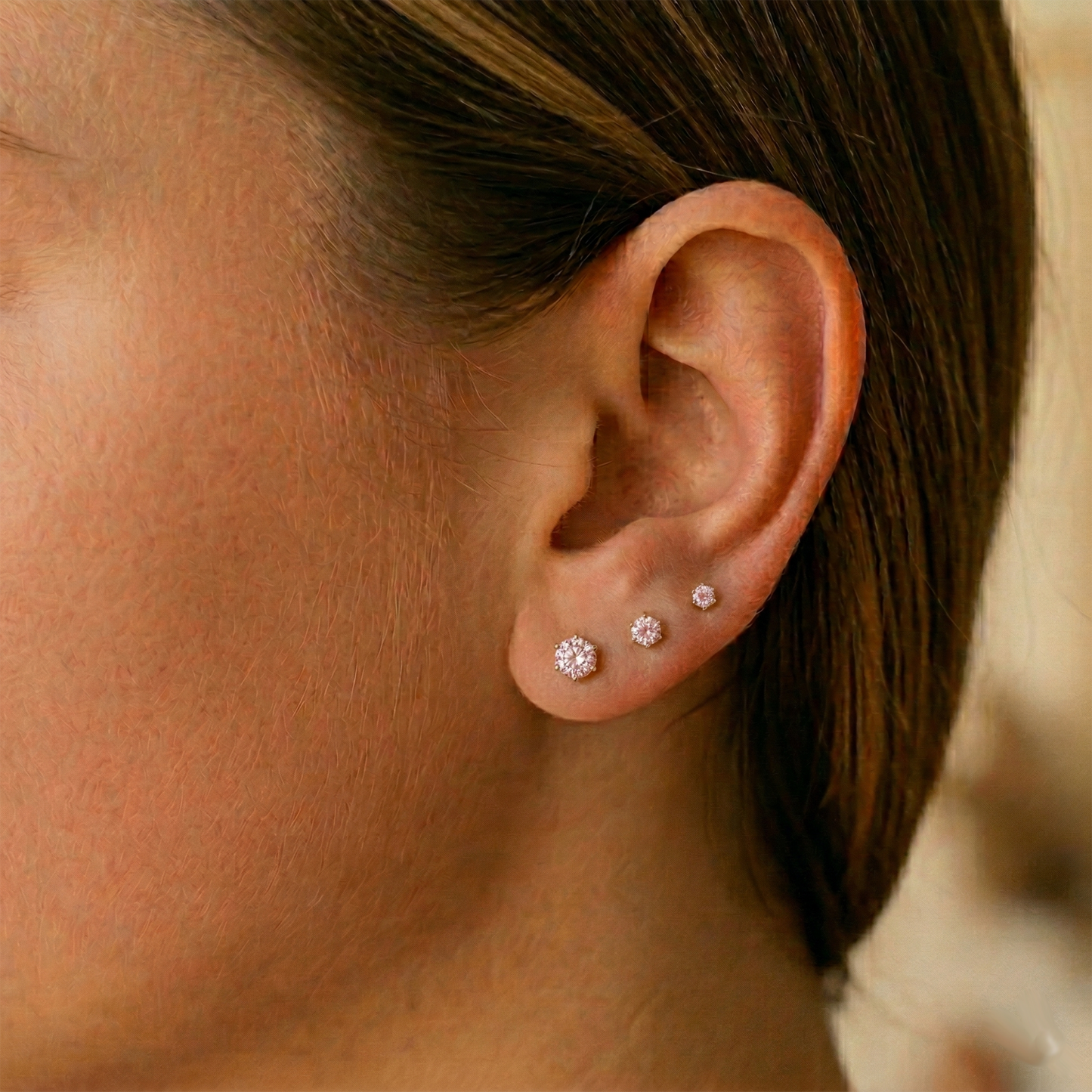 Pink CZ surgical steel stud earrings shown on ear with lobe piercing