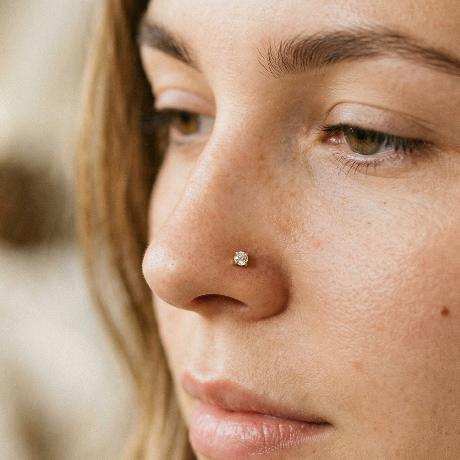Gold titanium CZ prong stud shown on nostril piercing
